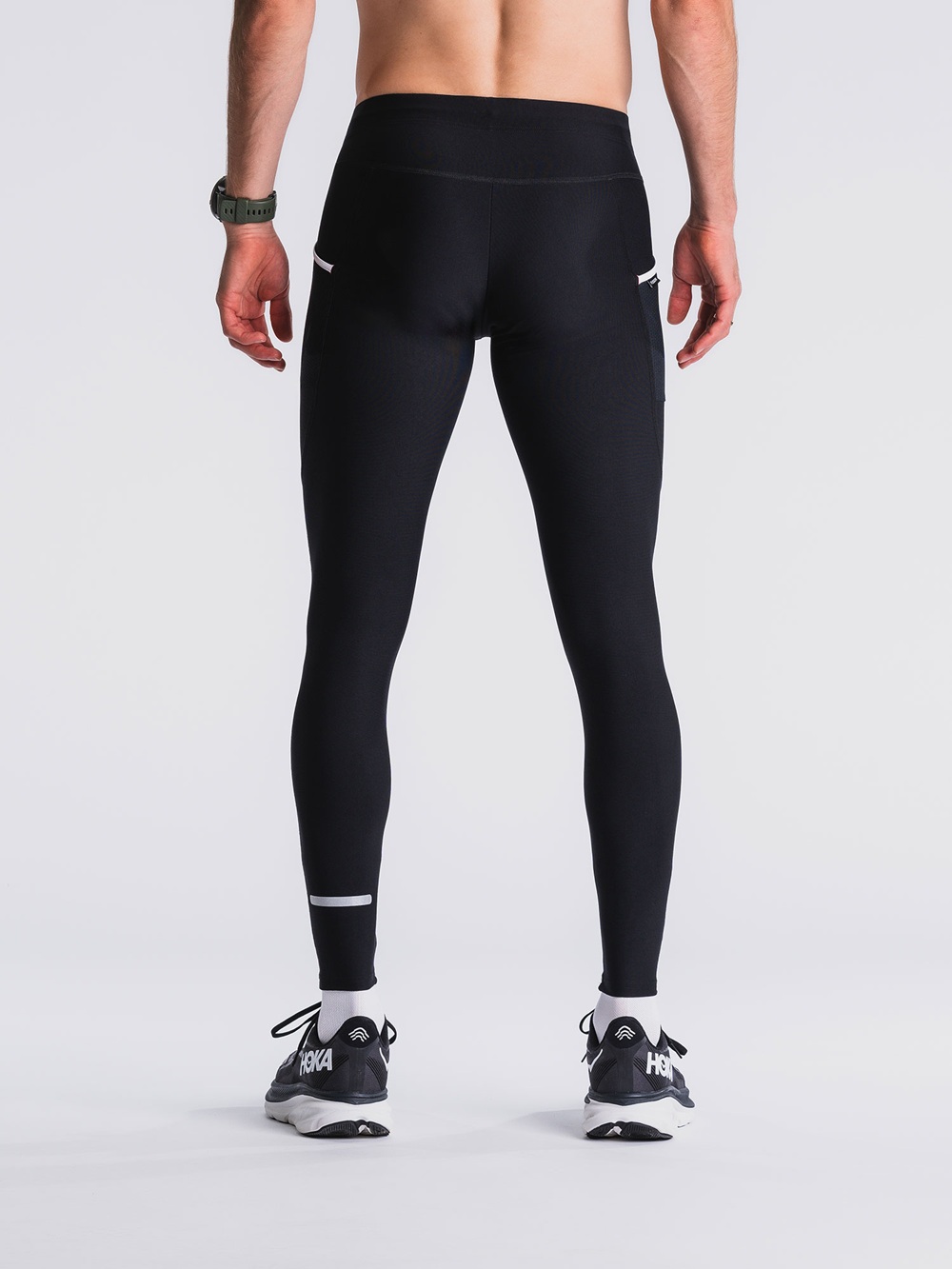 schwarzen Fusion C3 Long Tights an einem männlichen Model – enganliegend, mit dezentem Reflexstreifen am Beinabschluss